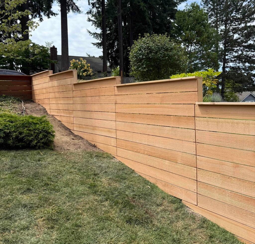 A modern cedar stepped fence on uneven ground following a steep backyard slope with perfectly level horizontal panels.