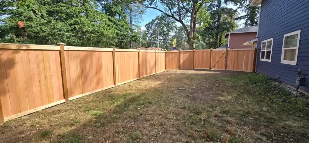 Completed backyard cedar fence and gate next to a house for Cedar Fence Installation in Lakewood WA.