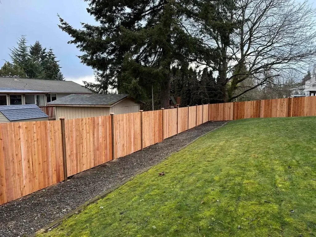 A long, new wooden boundary stretching around a grassy backyard following a rambler-style cedar fence replacement in Federal Way WA.