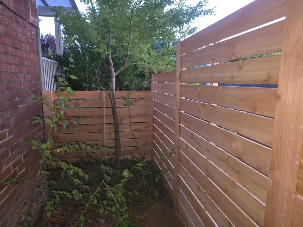 Horizontal wood fence built around existing yard vegetation in Portland, OR